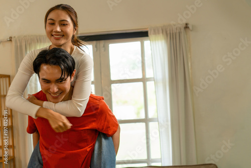 Playful Young Asian Couple Enjoying a Piggyback Ride at Home