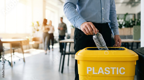 Man putting plastic bottle into yellow recycling bin in office