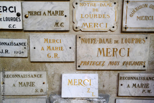 Marble ex-voto plaques on a church wall expressing gratitude to Notre-Dame de Lourdes for answered prayers. Annecy. France.