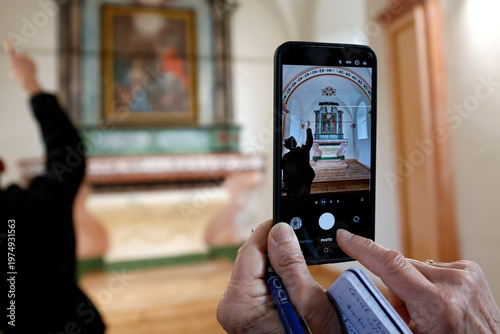 Baroque chapel of Bonnay. Woman with colorful bracelet photographs the restored retable on her mobile phone.  Saint Gervais.  France.