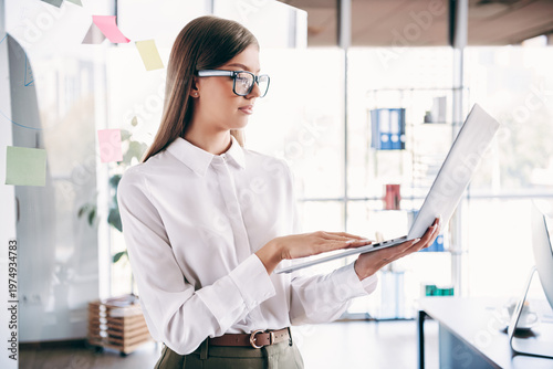 Bilde på lerret Professional businesswoman working on laptop in a modern bright office with stic