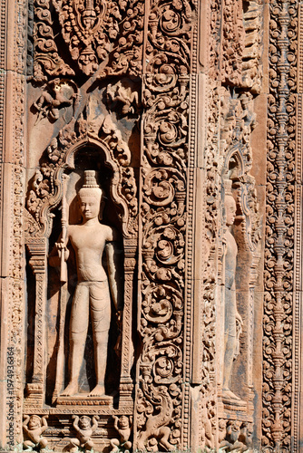 Sunlit carvings on Banteay Srei sanctuary doorway reveal guardians, foliage motifs, and legendary scenes in exquisite detail.   Siem Reap. Cambodia.
