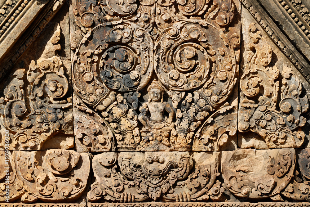 Obraz premium Sunlit carvings on Banteay Srei sanctuary doorway reveal guardians, foliage motifs, and legendary scenes in exquisite detail. Siem Reap. Cambodia.