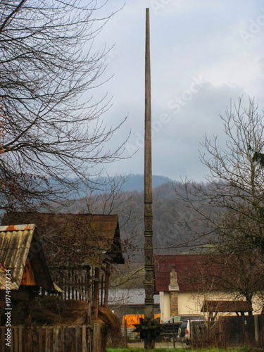A tall carved wooden spire serving as a landmark in the center of a village