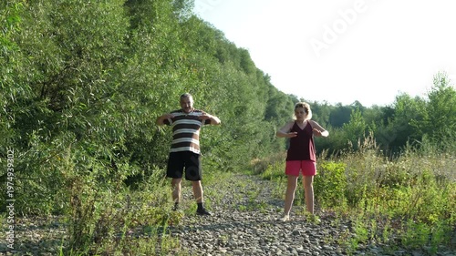 A man and a woman are doing fitness in nature.
