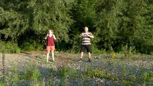 A man and a woman are doing fitness in nature.