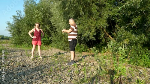 A man and a woman are doing fitness in nature.