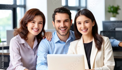 Three team members smile while sitting together in a modern office. They interact around a laptop, sharing ideas and enjoying their time at work