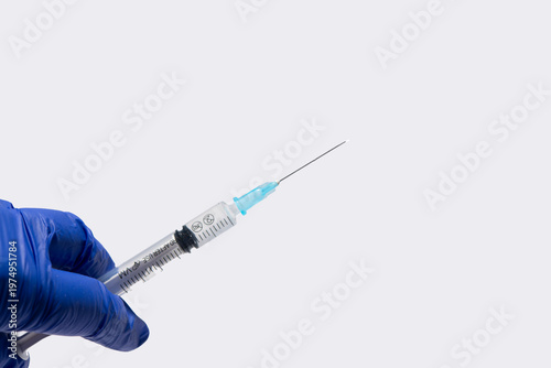 syringe with an injection is held in a gloved hand