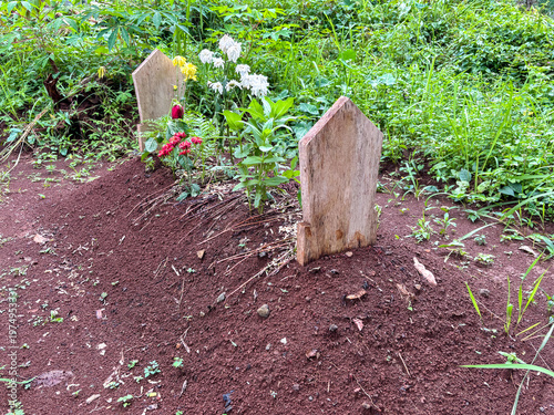 Foto Small humble grave with wooden headstones and fresh flowers in a rural cemetery