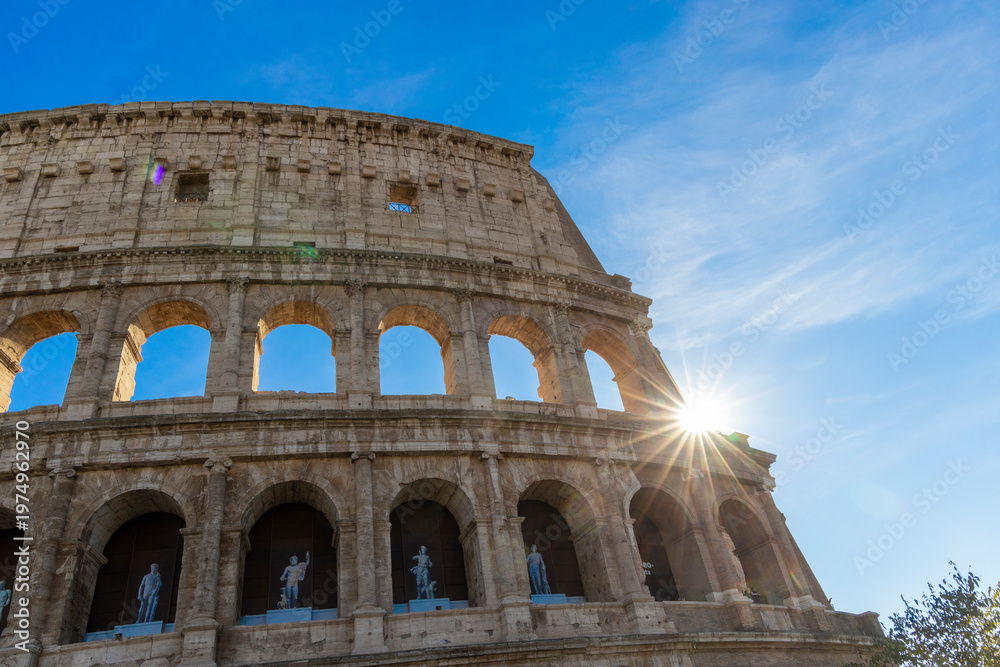 Obraz premium Famous Coliseum in Rome. Colosseum, or Coliseum. Sunset at huge Roman amphitheatre, Rome, Italy, Europe. Famous touristic place in the world and Europe. Beautiful blue sky background.