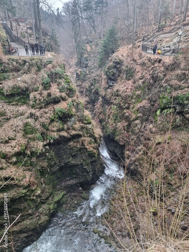 Wilczki Waterfall in Międzygórze, wild mountain landscape with flowing water, rocks and forest gorge, natural beauty and power of nature.
