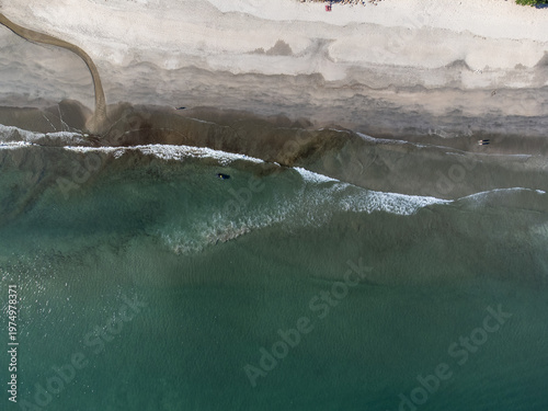 Aerial top down view of a river meeting the ocean on Boraceia beach sand patterns