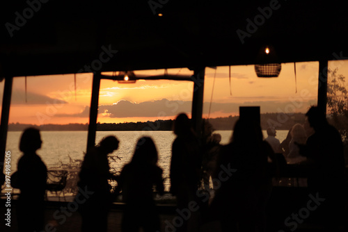 People Enjoying Sunset at Waterfront Restaurant