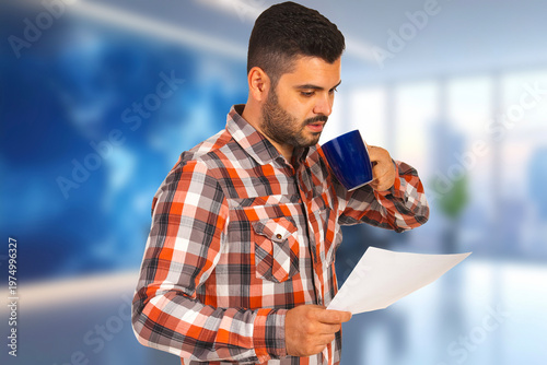 Man sips coffee while reviewing documents