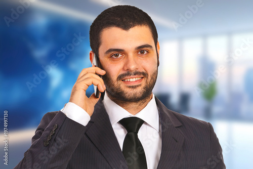 Man in suit smiles while talking on mobile phone