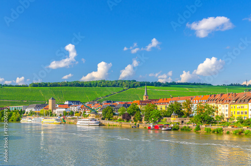 Wurzburg old town altstadt with old colorful houses on Main river embankment in Wurzburg city historical center Mitte, vineyards on green hill background in sunny summer day, Bavaria state, Germany