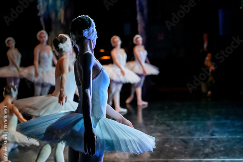 ballerina performing on stage in a ballet production in white costume.