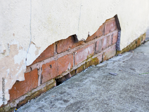 Peeling paint revealing brick wall damage and cracks