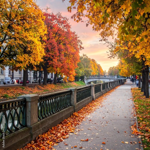 A vibrant autumnal scene of a pathway alongside a waterway bordered by trees. Golden and red foliage covers the branches and the ground