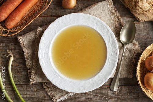 Chicken soup or bone broth in a white plate, top view