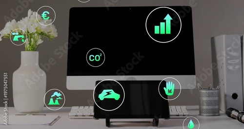 Displaying central desktop monitor and tablet showing green icons on clean desk, keyboard, vase