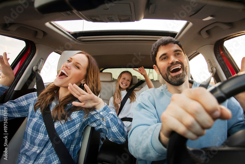 Foto Three family members having joyful car ride, singing and dancing together during