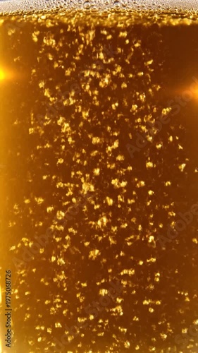 A close up view of golden liquid with many rising bubbles inside a glass container