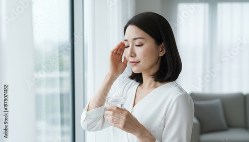 梅雨時の低気圧による頭痛で窓辺でこめかみを押さえる女性 Free Download 梅雨時の低気圧による頭痛で窓辺でこめかみを押さえる女性 - GFXLoad