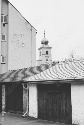 Black and white vertical shot of historical garage doors and rooftops with the Old Town Hall tower in Litomyšl in the background, Czech Republic.