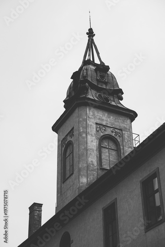 Black and white vertical shot of a historical building tower with ornate windows and a decorative spire in Litomyšl, showcasing classic European architecture and urban heritage.