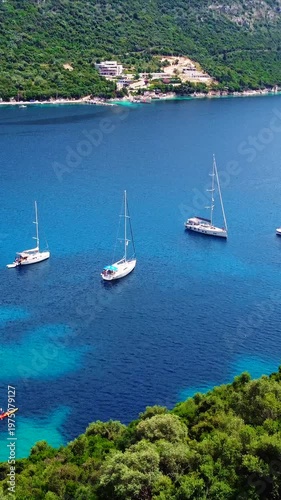Wallpaper Mural Vertical aerial of sailboats in calm turquoise Rouda Bay at Mikros Gialos Beach, surrounded by lush green mountains, Mediterranean summer scene Torontodigital.ca