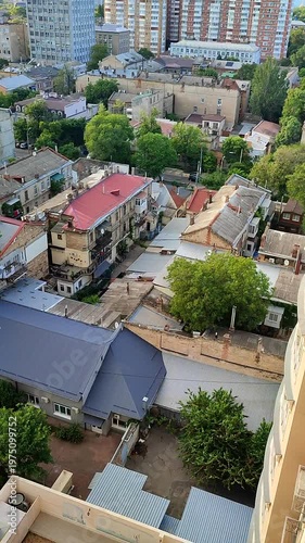 Cityscape. Old buildings with roofs, green trees, road on sunny summer day. Windows and walls of old houses, multi-story buildings and green vegetation in city. City scenery. Urban landscape Vertical