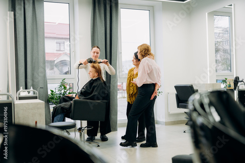 Billede på lærred In a bright salon, a stylist skillfully styles a client's hair