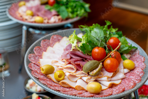 Assorted meat platter with sliced ham, salami, olives, and cherry tomatoes