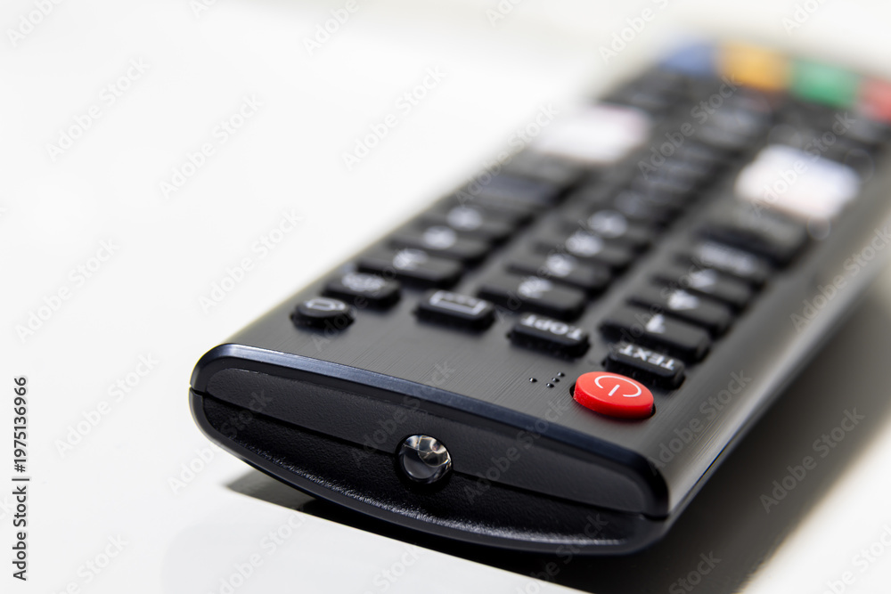 Obraz premium Remote control close up on white surface with power button focus