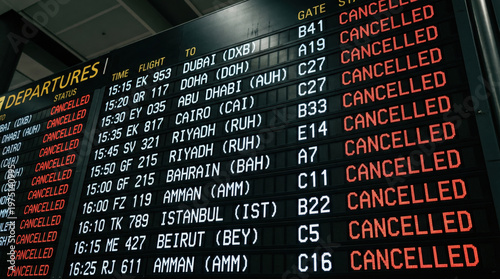 Airport departure board with all flights marked as cancelled. Digital information screen showing travel disruptions. Middle East conflict, delay and cancellation concept