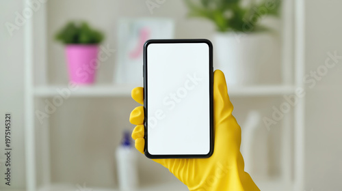 Person wearing yellow gloves holding blank smartphone screen in home setting