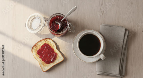 Top view of toasted bread with berry jam, black coffee, and an open jam jar on a light wooden table.