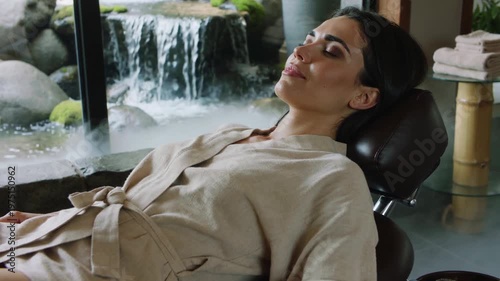 A serene woman enjoys a peaceful spa treatment with a waterfall view.