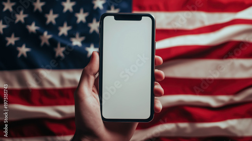 Hand holding smartphone with blank screen in front of american flag