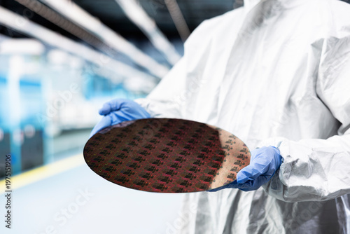 Foto Holding processed silicon wafer, cleanroom and technician in automated fabrication plant