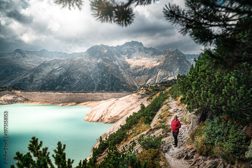Foto Lone female hiker observes and is worried about the depleted Lake Gelmer reservoir in Switzerland due to climate chance, ideal for environmental theme, climate concept and renewable energy