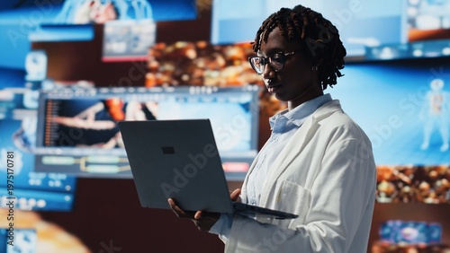 Fotografie Female scientist looking at genomes on laptop screen, comparing infection models