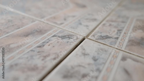 Loose Floor Tile Inspection Close-Up: Tiler Pressing Uneven Ceramic Tile That Moves and Lifts Above Floor Level | Home Repair and Maintenance Concept