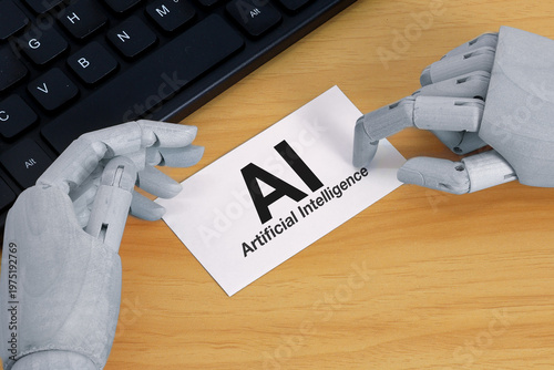 Robotic hands holding “AI artificial intelligence” card on desk with keyboard background, representing modern technology, automation, and digital innovation.
