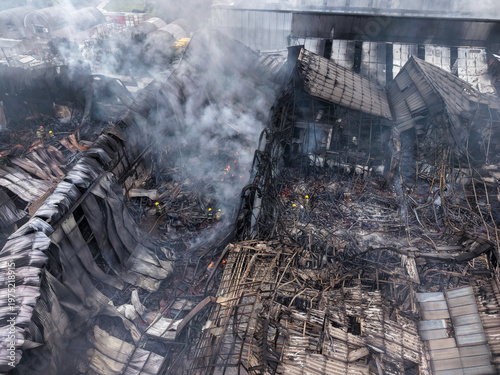 Aerial drone view of firefighters among ruins of a large scale industrial warehouse fire