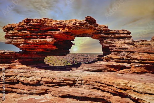 Kalbarri National Park sunset through red sandstone rock arch over rugged desert landscape