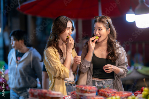 Friends eating fruit at vibrant asian night market