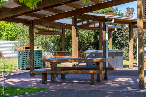 Obraz na plátne Covered picnic area with timber shelter, seating, and waste bins in a public park in Australia